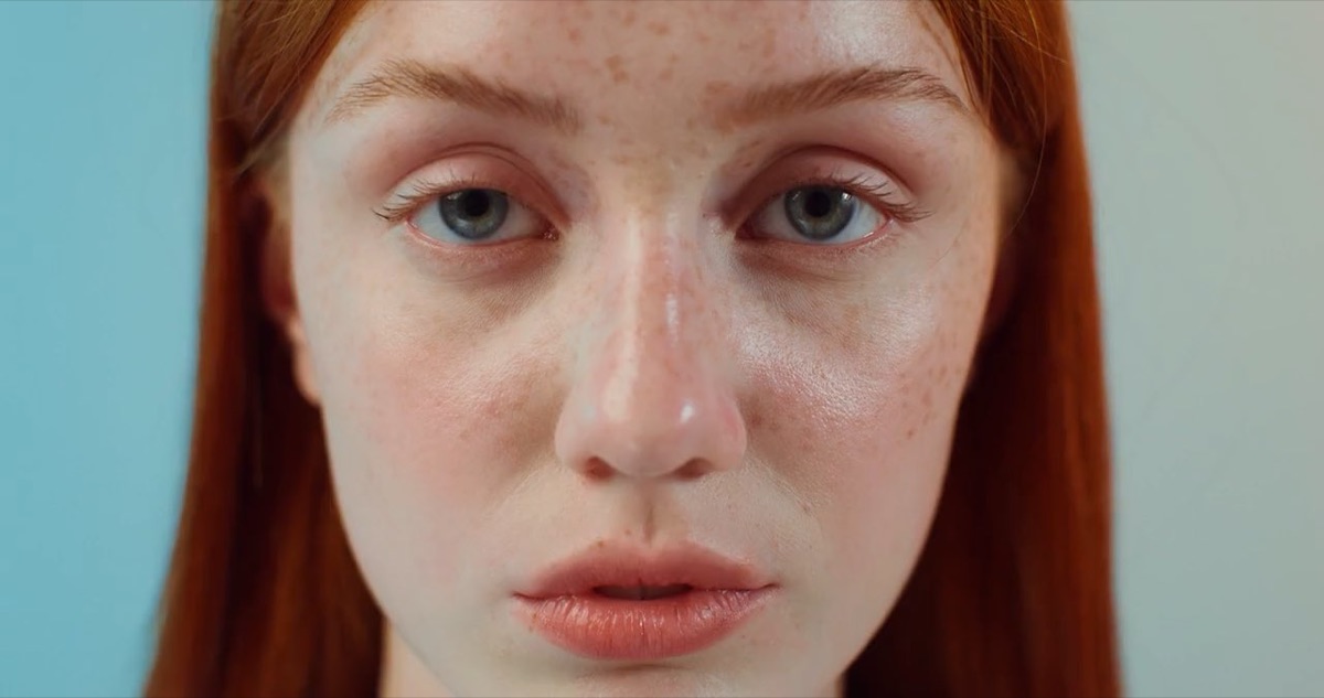 A Thea member with red hair and freckles, looking straight at the camera